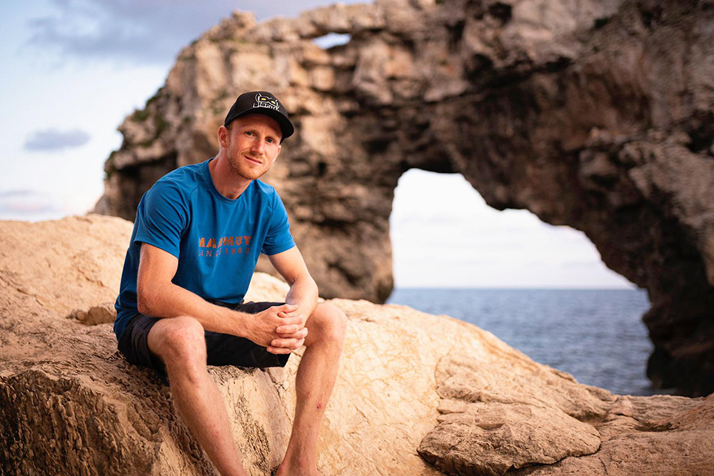 30-letni Austriak Jakob Schubert pokonał jedną z najsłynniejszych dróg DWS (Deep Water Solo) na Majorce - "Es Pontas", biegnącą charakterystycznym skalnym łukiem (widocznym w tle); fot. Sebastian Marko / Alpsolut